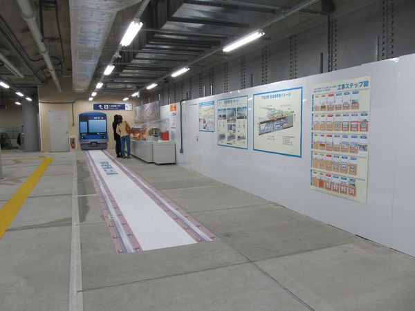 コンコース奥に設置されている地下化工事の情報コーナー。床には将来の線路位置を示すステッカー。